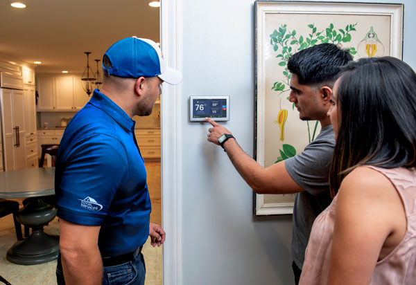 Total Services Heating and Air Conditioning demonstrating a smart thermostat for a customer.